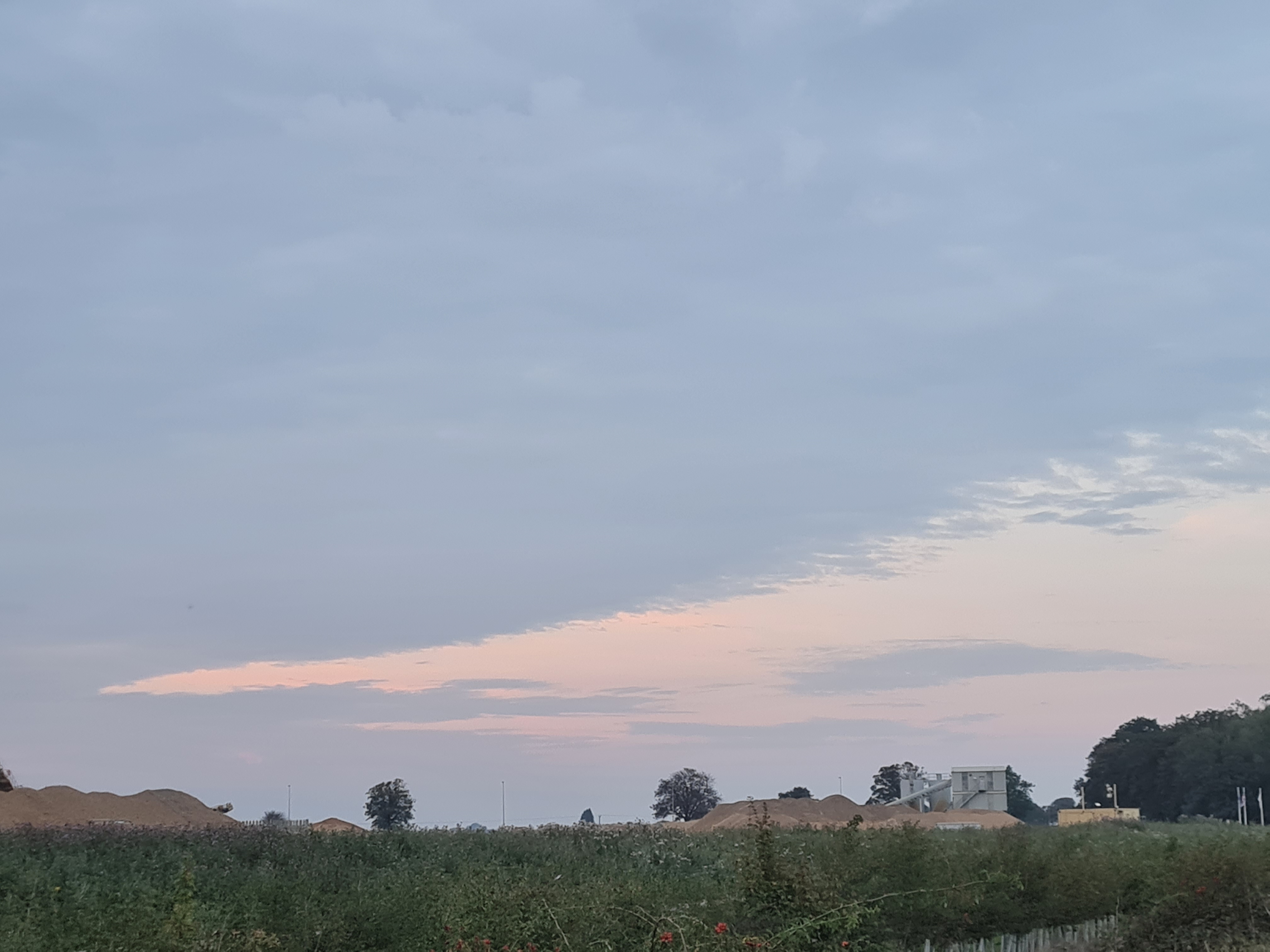 Photo of Willow Hall Lane, Peterborough - Industrial aggregate piles and clouds at dusk