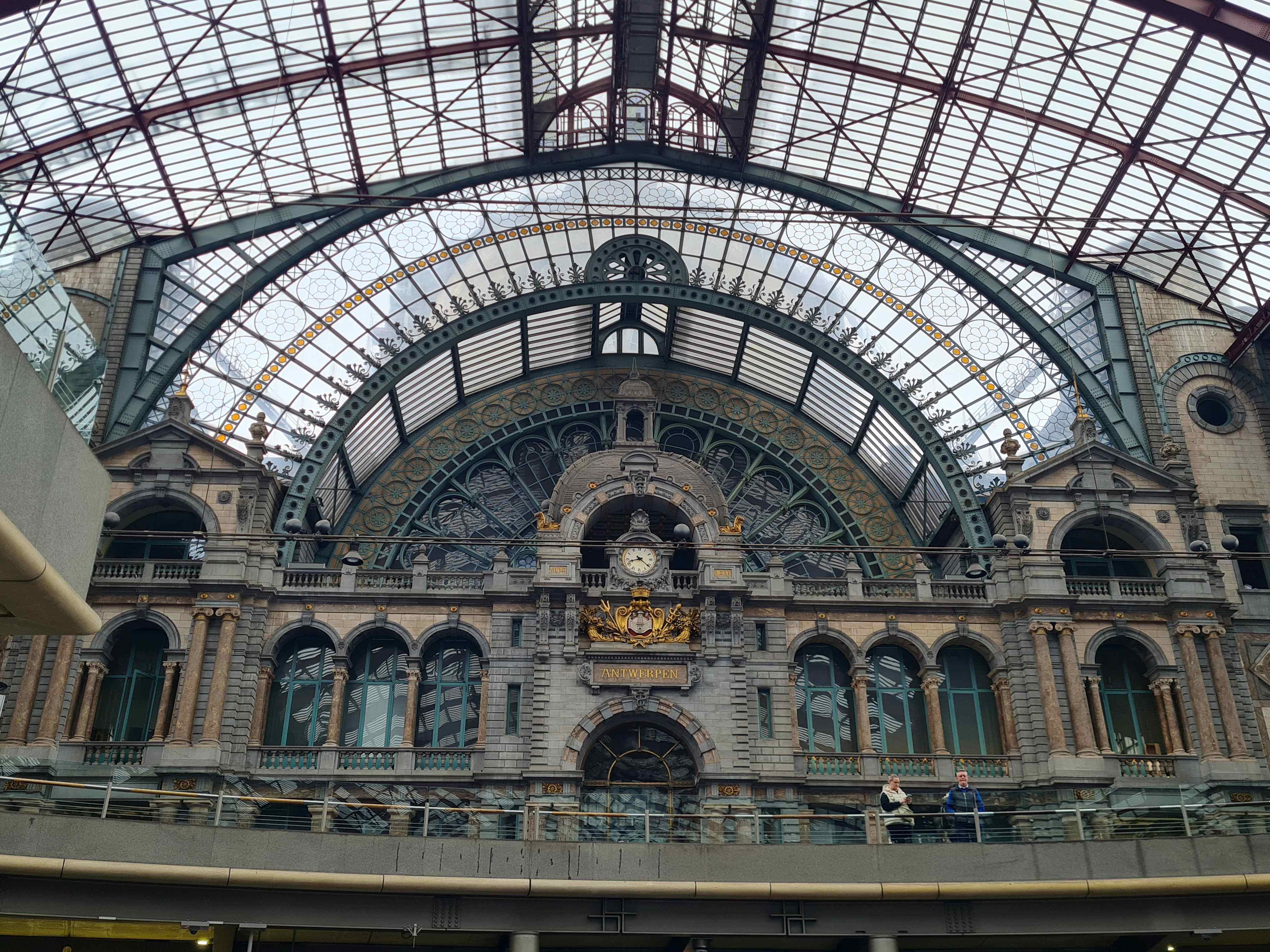 Photo of Ornate stonework, clock and roof at Antwerpen Centraal